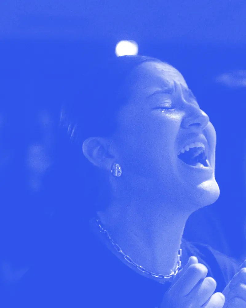 Mulheres cantando de olhos fechados no louvor, na Conferência ONE 2025